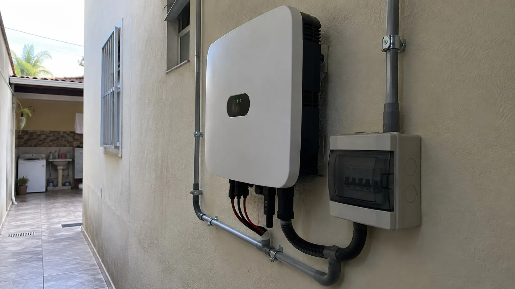 Inversor solar e conduítes organizados em uma área protegida de uma casa.