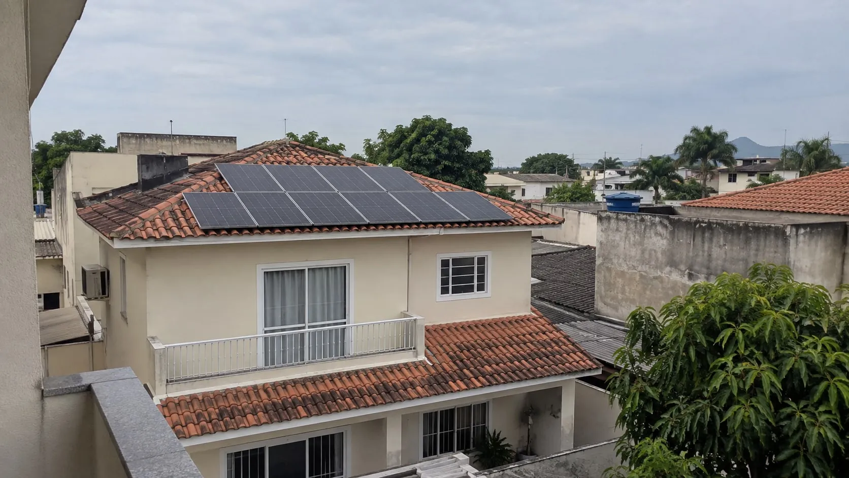 Placas solares no telhado de uma casa entre sobrados e vegetação de Campo Grande, no Rio de Janeiro.